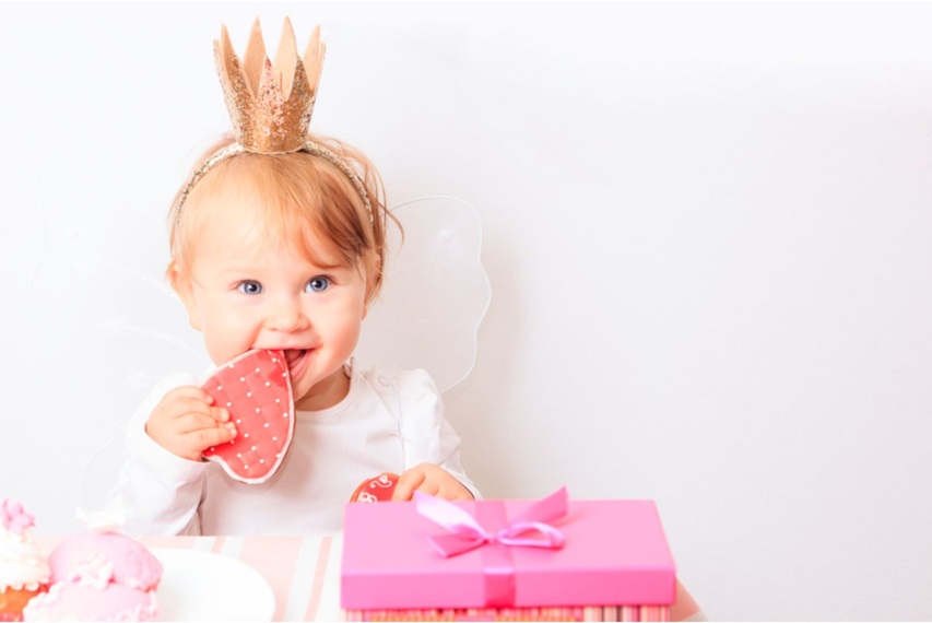 Eine kleine Geburtstags-Prinzessin knabbert an ihrem Geburtstagskuchen